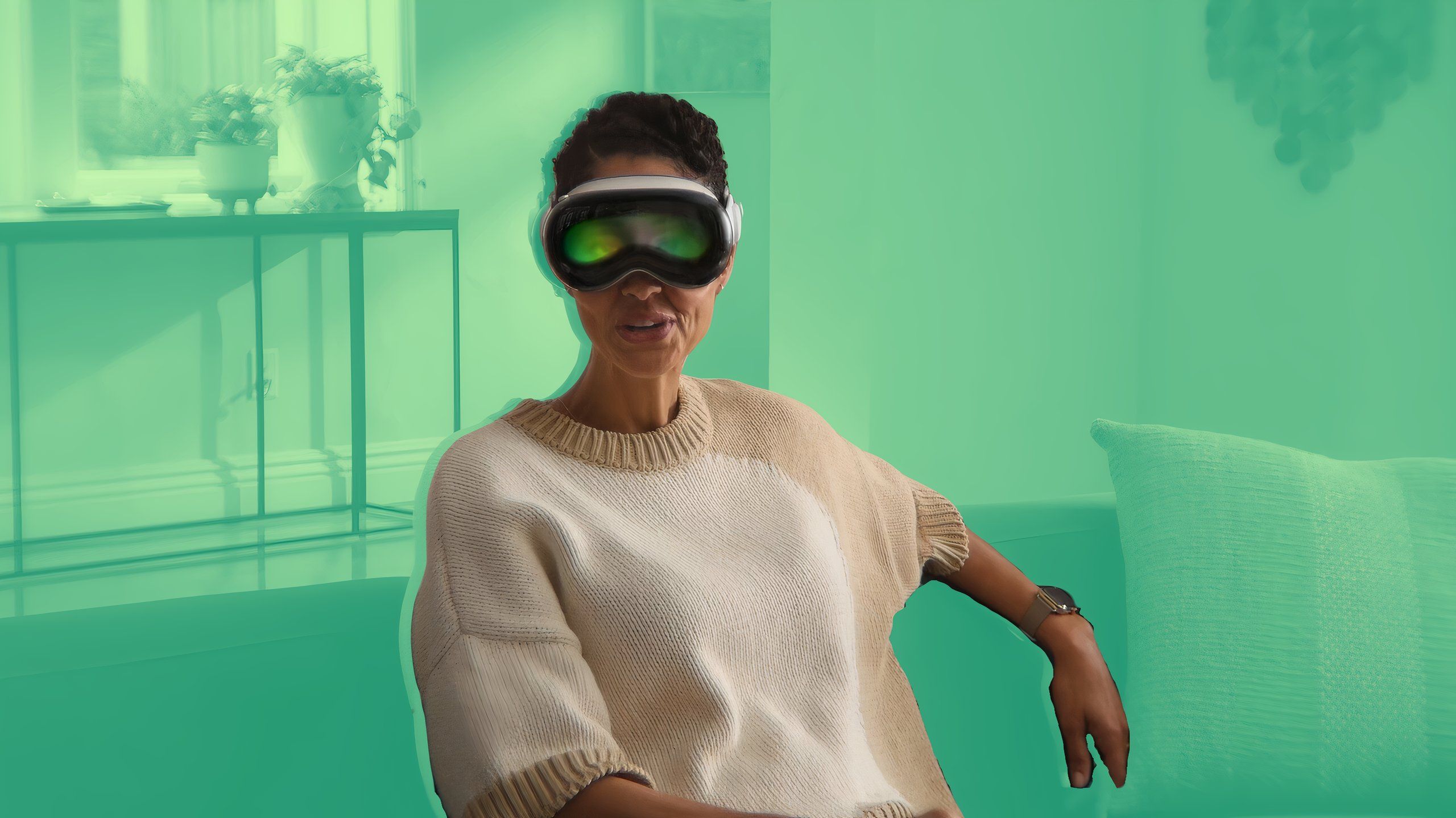 A woman sitting on a couch wearing a Vision Pro over a green background.