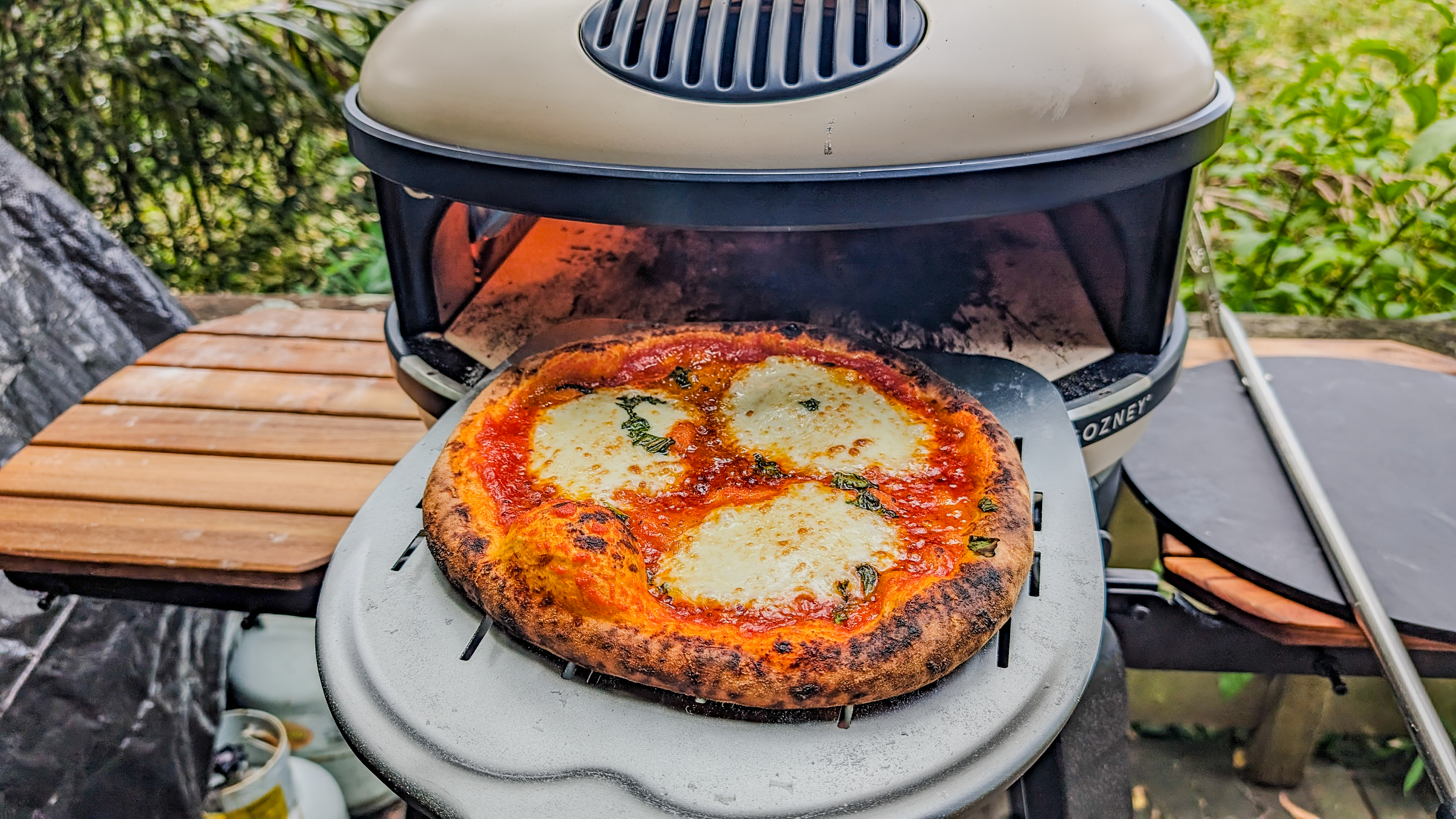 A cooked pizza on a peel coming out of the Gozney Arc XL pizza oven