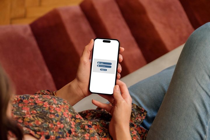 Login screen on an iPhone held by a woman.