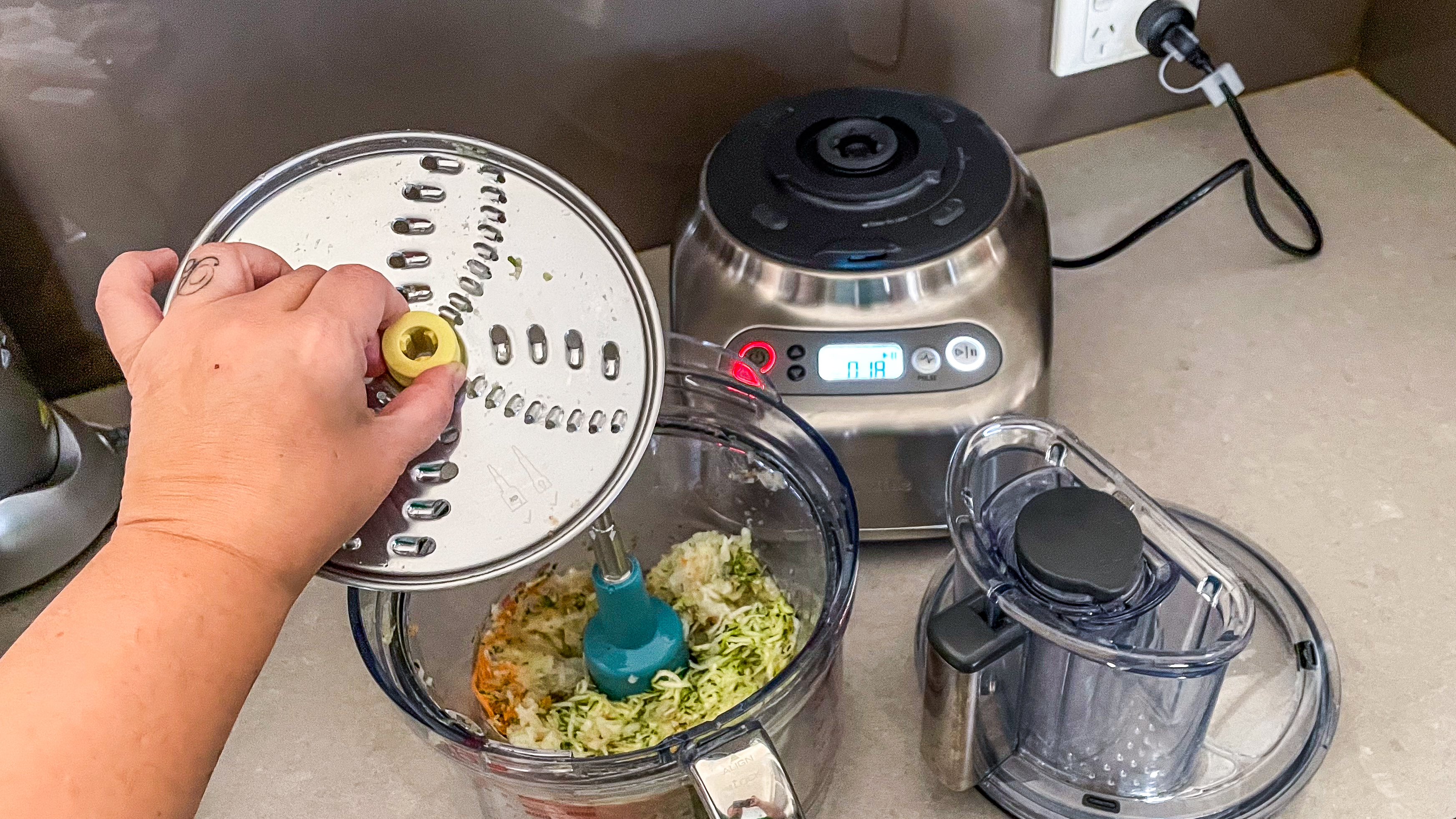 A hand removing the grater attachment from the bowl of the Breville Paradice 16