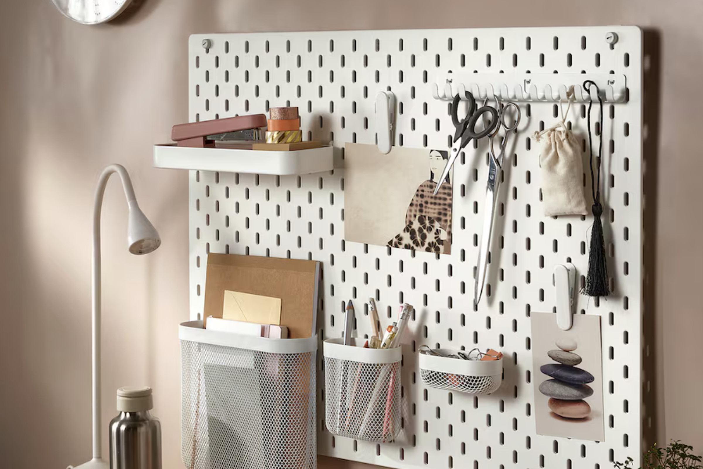 White pegboard with a variety of tools hanging from it.