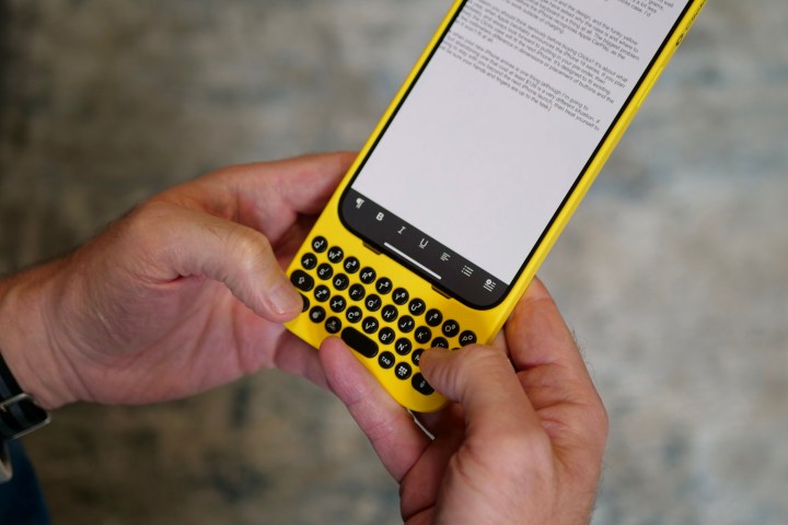 A person holding the iPhone 15 Pro Max inside the Clicks Keyboard case.