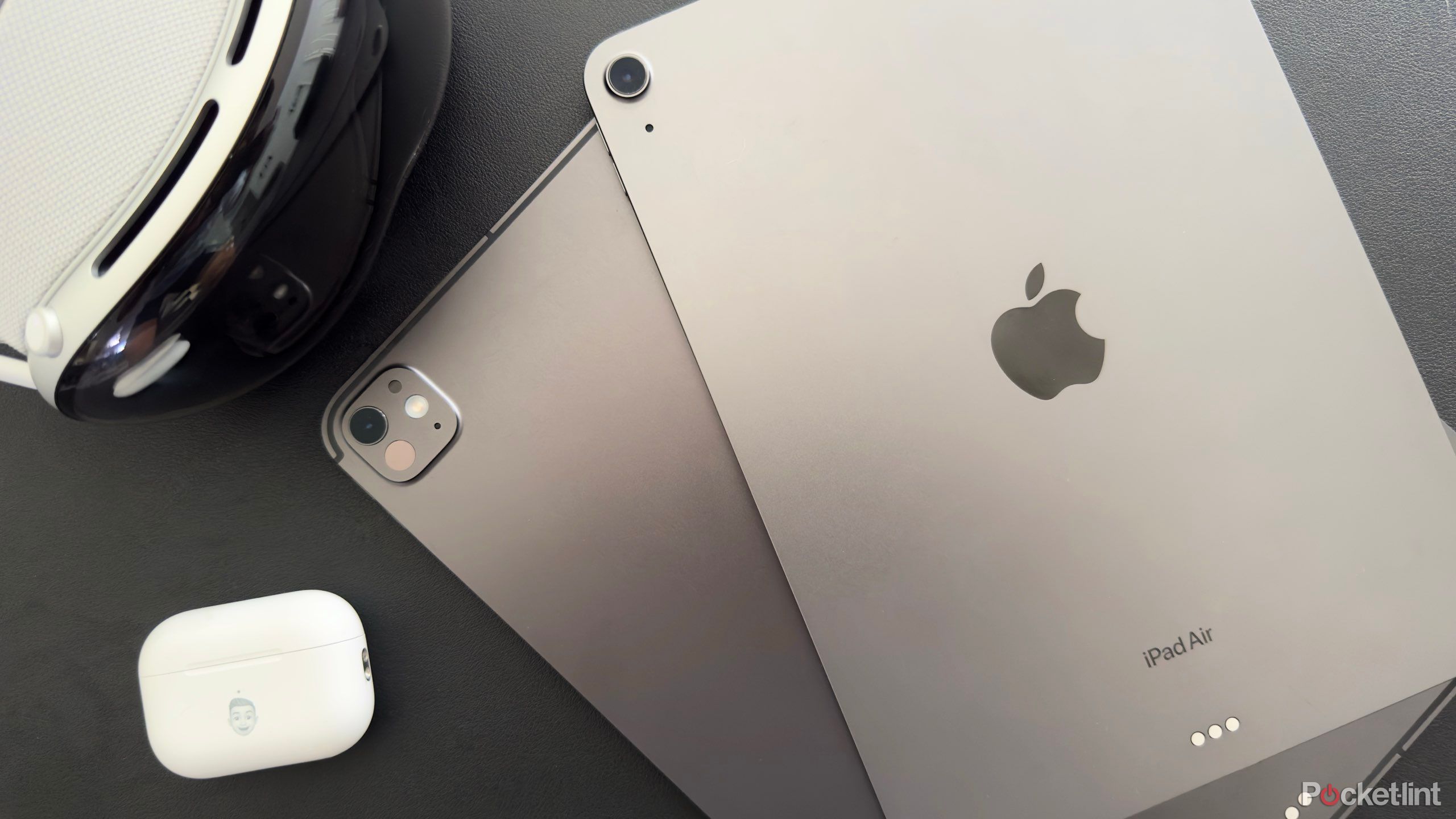 Two space grey iPads next to an Apple Vision Pro and AirPods Pro.