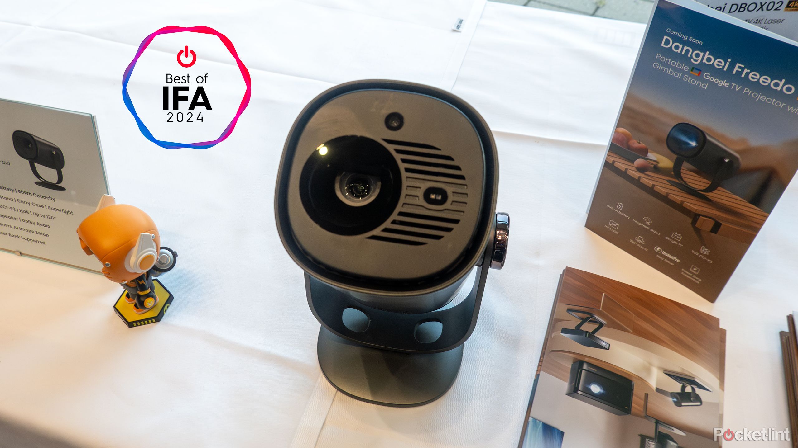 The Dangbei Freedo projector sits on a table with pamphlets. 