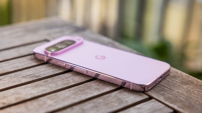 A Google Pixel 9 Pro smartphone in a purple finish resting on a wooden table.