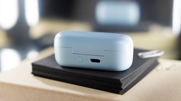 Light blue Sony WF-C510 charging case sitting on a stack of black notebooks.