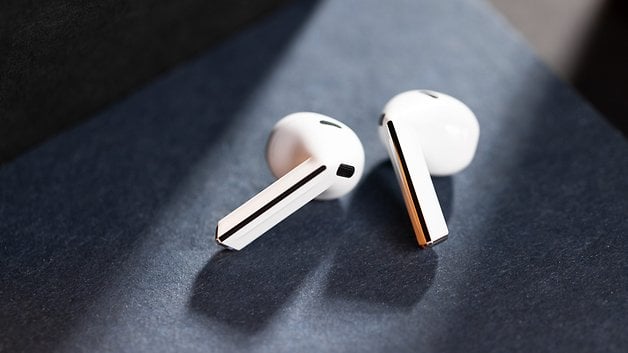 Samsung Galaxy Buds 3 resting on a dark surface, highlighting their sleek white design.