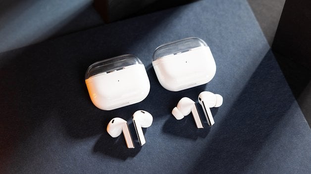 Two pairs of Samsung Galaxy Buds 3 wireless earbuds with their charging cases on a dark surface.