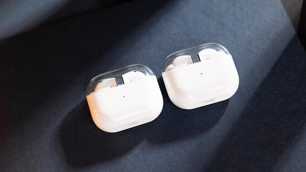 White wireless earbuds in its charging case on a dark surface.