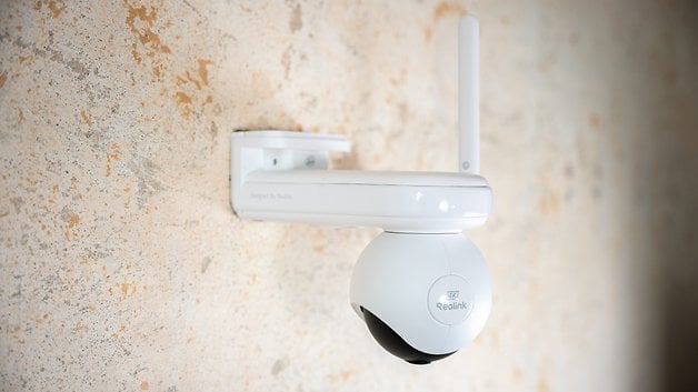 A white Reolink Atlas PT Ultra camera mounted on a textured wall.