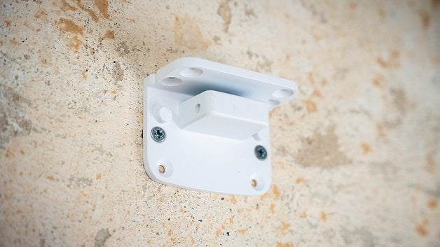 A white bracket attached to a textured wall.