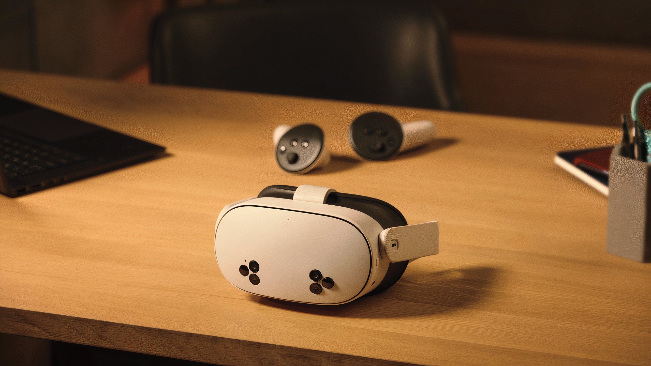 A white VR headset with six black cutouts on the front laying in front of some round VR controllers.