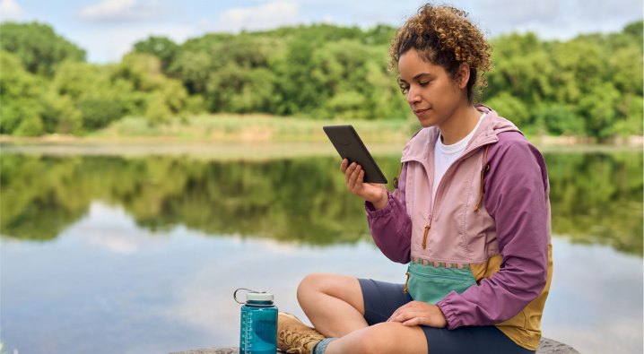 Amazon Kindle Paperwhite 2024 12th-generation being used outside by a lake