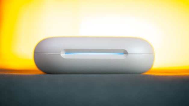 A white charging case for the Soundcore Aerofit 2 earbuds, illuminated by a soft, yellow background.