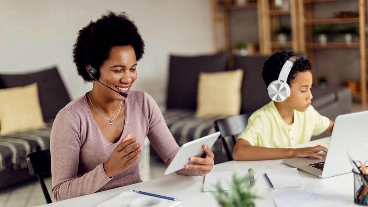 A woman and child using headsets to voice chat on a tablet and laptop.