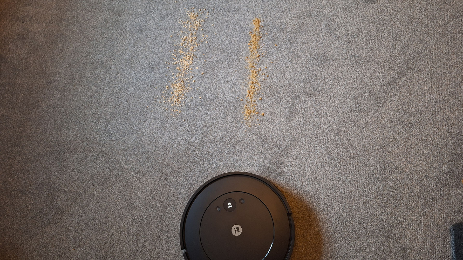 iRobot Roomba Combo Essential before the vacuuming test on carpet, with lines of cookie dust and oats on the floor in front of it