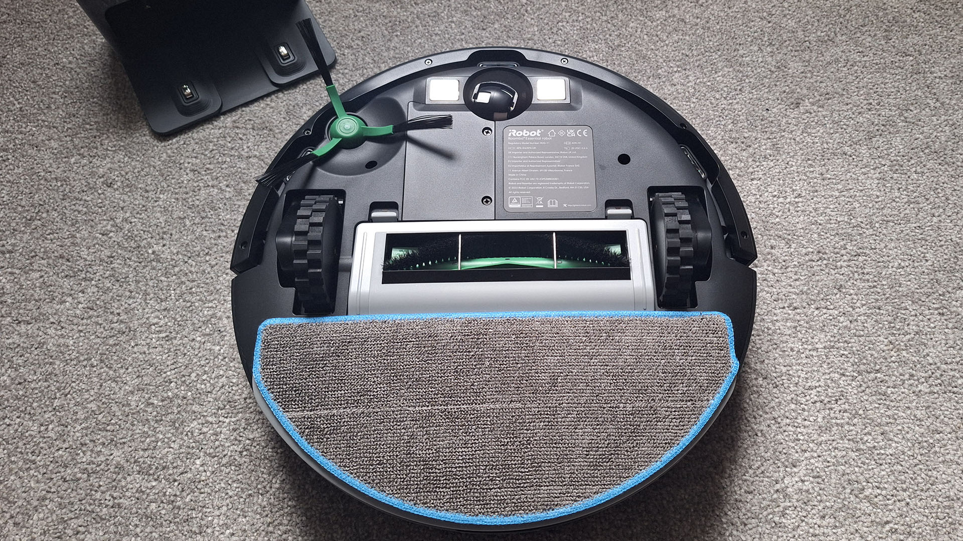 Roomba Combo Essential robot vacuum flipped over to show brushroll and mop pad