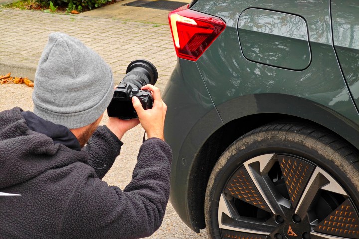 A person taking a photo of a car.