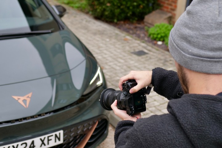 A person taking a photo of a car.