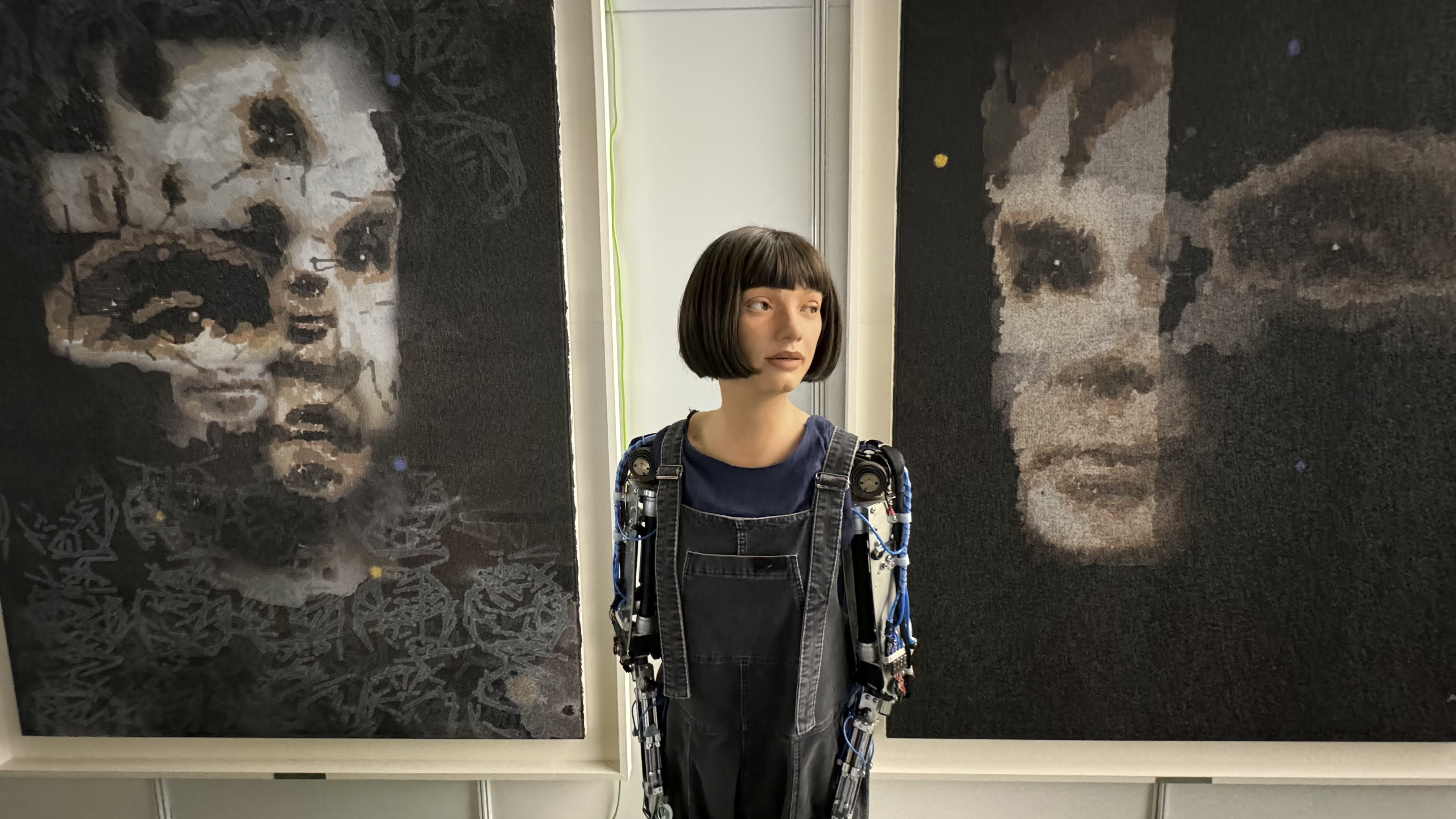 The Ai-Da robot standing in front of her 'AI God' painting on Alan Turing