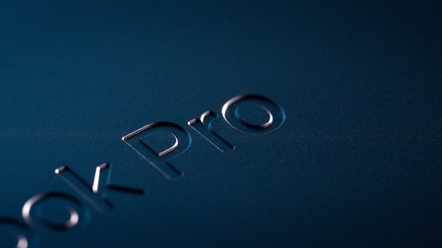 Close-up of the 'MacBook Pro' logo on a dark surface.