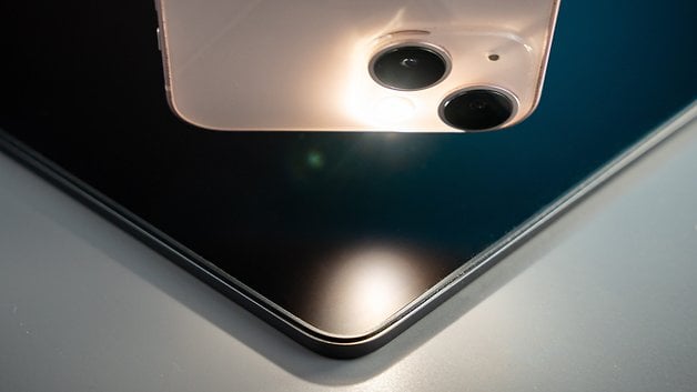 Close-up of a smartphone hovering over the dark surface of a MacBook Pro.