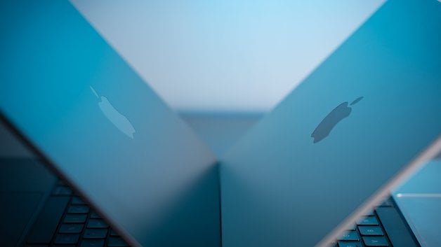 Two Apple MacBook Pro laptops facing each other, showcasing their sleek designs and iconic logos.