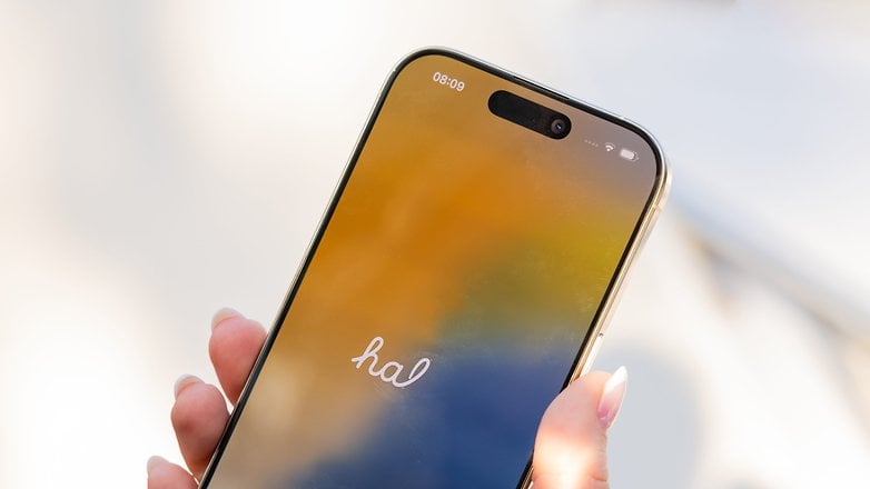 A hand holding an iPhone 16 Pro displaying the time 08:09 and the word 'hal' on the screen.