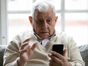 Shocked older man looking at smartphone screen.